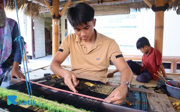 Thumbnail Tangan Mario tampak kaku saat awal mencoba belajar tenun. (Foto: Samsul Hadi Mustofa/Ketik.co.id)