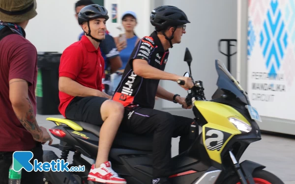 Thumbnail Pembalap MotoGP tim Aprilia Maverick Vinales dibonceng salah satu kru timnya (13/10/2023). (Foto: Naufal/Ketik.co.id)