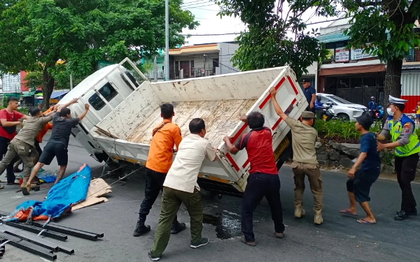 Thumbnail Hindari Mobil, Truk Muatan Besi Talang Terguling di Sukomanunggal Surabaya