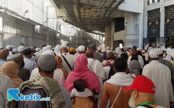 Thumbnail Seorang ibu itu menggedong buah hatinya di punggung sambil berjalan menuju ke Masjidil Haram (7/6/2024). (Foto: Muhsin Budiono/Ketik.co.id)