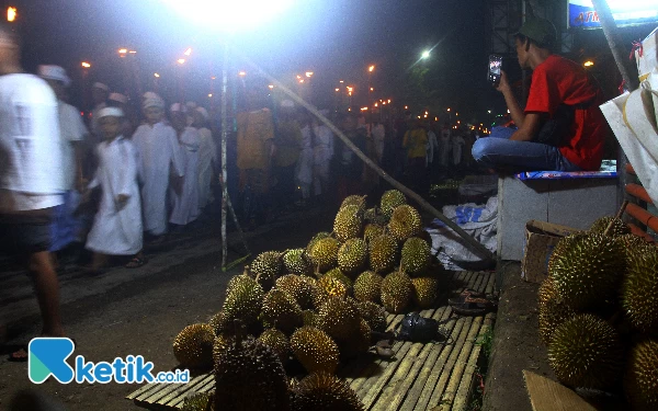 Thumbnail Dengan menggunakan handphone tampak penjual buah durian mengabadikan momen pawai obor untuk menyambut bulan suci Ramadhan 1445 H oleh para santri Majelis Taklim An Nur Palembang, Sabtu (9/3/2024). Para peserta pawai obor yang melintasi Jalan. KH Wahid Hasyim dan menuju Jalan. Walikota H Husni dan kembali ke Majelis Taklim An Nur Jalan. H Faqih Usman Seberang Ulu 1 Palembang. (Foto: Wahyu Rahmanto/Ketik.co.id)