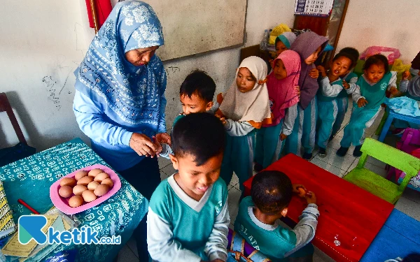 Thumbnail Seorang guru membagikan telur rebus kepada murid-murid di TK Bustanul Athfal Wirosari, Kabupaten Grobogan, Jawa Tengah, Sabtu, 14 September 2024. Selain bekal yang dibawa masing-masing murid, pihak sekolah juga membagikan snack tambahan yang kaya akan protein hewani sebagai upaya memenuhi asupan gizi dan pencegahan stunting sejak dini. (Foto: Achmad Fazeri/Ketik.co.id)